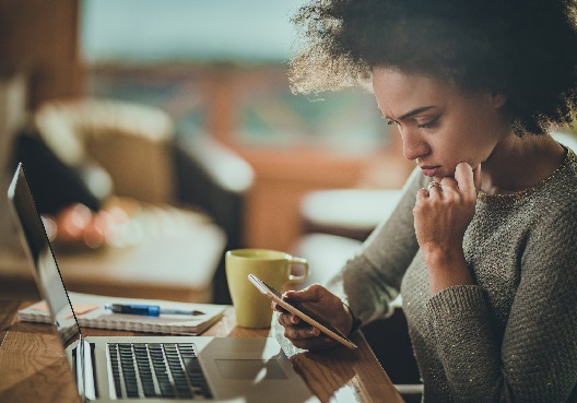 A young woman reads tips to help spot scams and frauds on her mobile phone. 